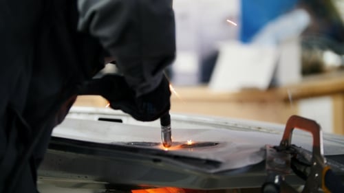 Person Welding Metal with Protective Gear in Workshop