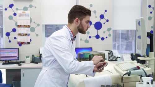 Man Enters Information From Computer To the Tablet at the Laboratory