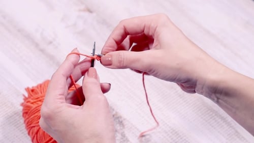 Hands Knitting with Bright Orange Yarn