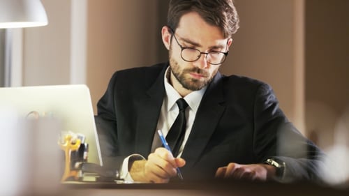 Man in Suit Writing at Desk