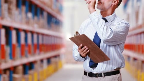 Male warehouse worker counting stocks and holding on clipboard