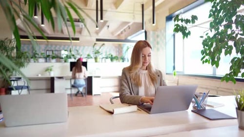 Young Businesswoman in Formal Suit Working at the Table in Modern Open Space Office