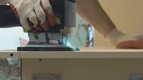 Master of Furniture Production Saws the Surface of the Table with an Electric Jigsaw. Close-up. Slow
