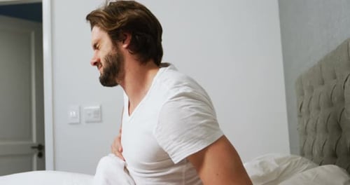 Jeune homme se réveillant dans son lit et étirant les bras