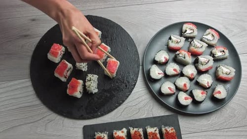 Hand Picks Up Sushi with Chopsticks