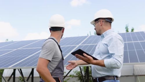 Two Workers in Helmets Check the Installed Solar Panels