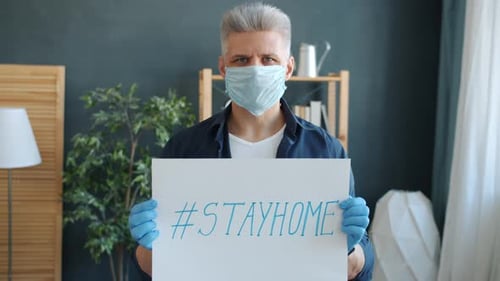 Man Wearing Mask Holding #StayHome Sign