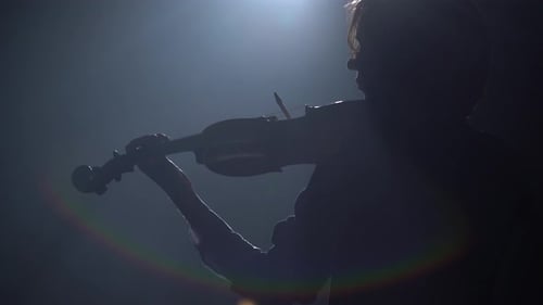 Girl in a Dark Studio Plays the Violin From a Lantern Glare Around the Room. Black Smoke Background