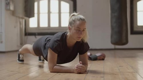Woman Exercises, Doing Plank in Bright Gym