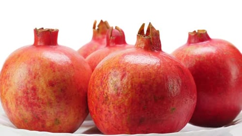 Pomegranates Rotating on a White Plate