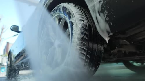 Pressure Washing a Car Tire in the Daytime