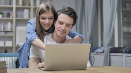 Smiling Couple Using Laptop in Home Setting