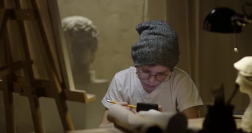 Teenage Boy Drawing and Using a Smartphone