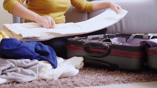 Young woman preparation suitcase getting ready for road trip preparing luggage for vacation.