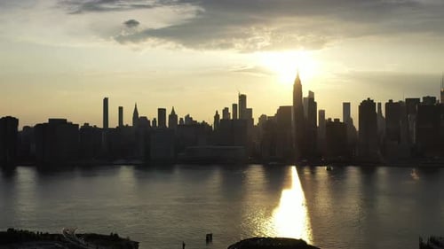 a slow dramatic pan right of a drone camera, aerial view of New York City's east side, during a gold