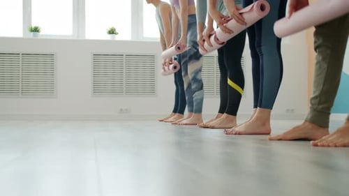 Low Shot of Yoga Class Students Unrolling Mats on Laminate Floor in Light Studio