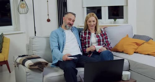 Casal sentado junto no sofá macio da sala de estar e conversando