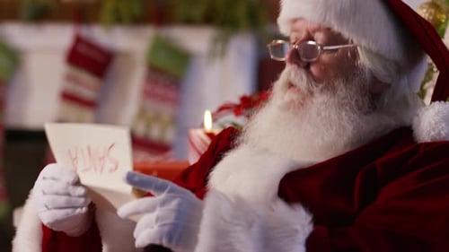 Santa Claus Reading a Letter Indoors at Christmas