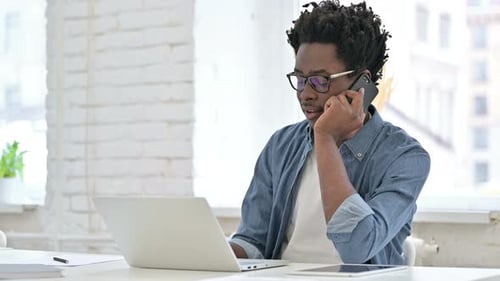 Young African Man Talking on Smartphone in Office