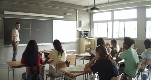Männlicher Mathematiklehrer schreibt während des Unterrichts Formeln an die Tafel