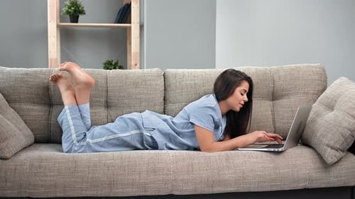 Woman Relaxing at Home Using Laptop on Couch