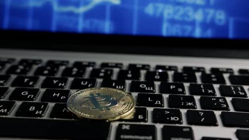 Bitcoin on Laptop Keyboard with Chart Background
