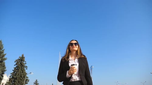 Young Businesswoman Holding Cup of Take Away Coffee and Walking Along Urban Street. Business Woman