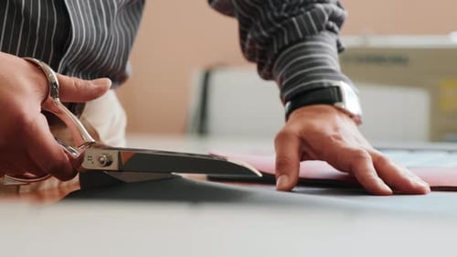 Close Up of Tailor Cutting Fabric with Scissors