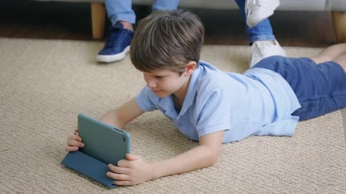 Boy Lying on Rug Uses Tablet Computer