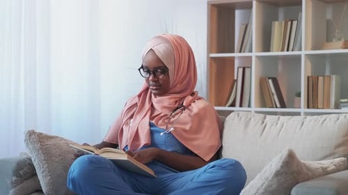 Woman Reading Book Wearing Scrubs and Headscarf