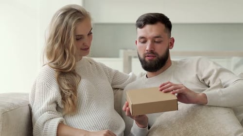 Young Couple Opening Gift Together Indoors