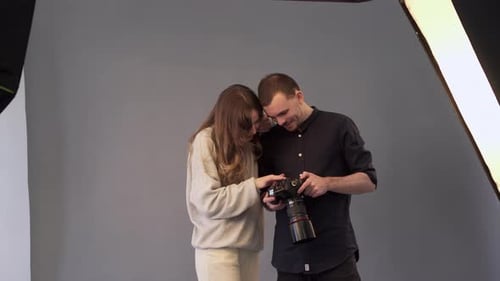 Man and Woman Examine Camera Display in Studio