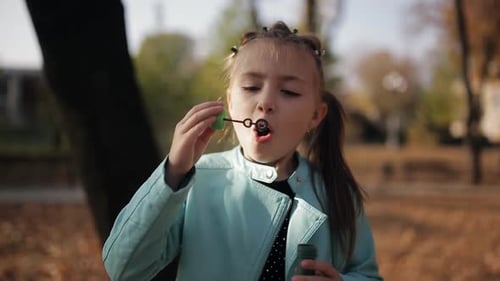 Girl Blowing Bubbles in Autumn Park