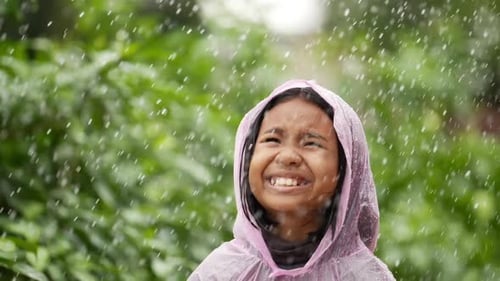 Smiling Girl Enjoying Rain Wearing Pink Raincoat