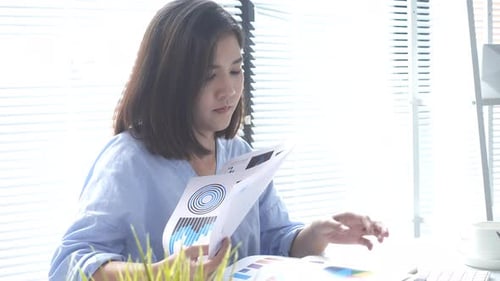 Woman Reviews Data and Types on Keyboard at Desk