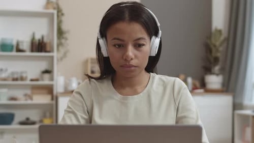 Woman Using Laptop with Headphones at Home