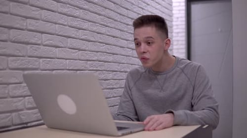 Enthusiastic Young Adult Video Calling on Laptop