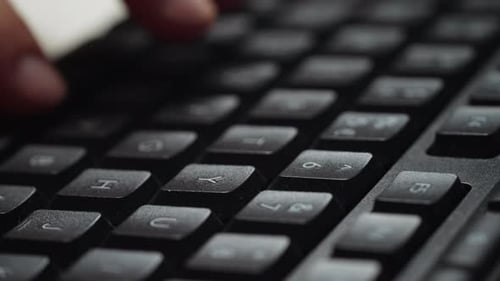 Close Up computer keyboard with fingers typing on it.