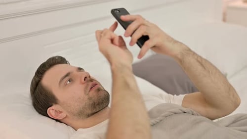 Young Adult Using Cellphone in Bed