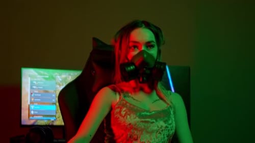 Jeune joueuse dans un respirateur noir assise près du PC de jeu