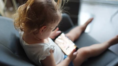 Child Sitting with Phone at Home During Day