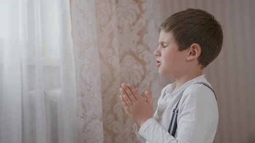 Boy Praying Quietly Indoors By Window
