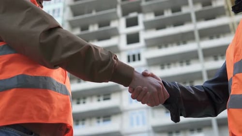 Friendly handshake of two builders at a construction site