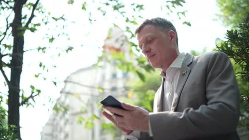 Man in Suit Using Phone Outdoors in Urban Setting