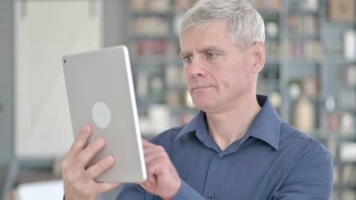 Retrato de homem sério de meia idade trabalhando no tablet