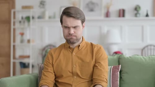 Man Thinking Deeply on Couch in Bright Room