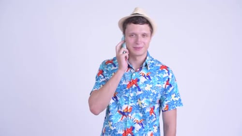 Man Talking on Phone Wearing Hawaiian Shirt and Hat