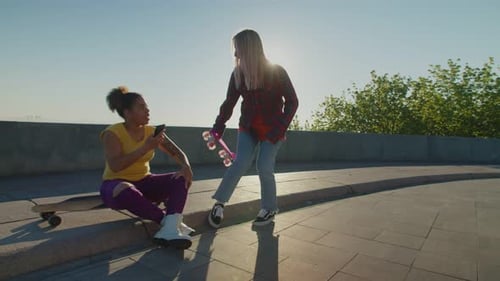 Two Friends Chatting on Skateboards Outdoors
