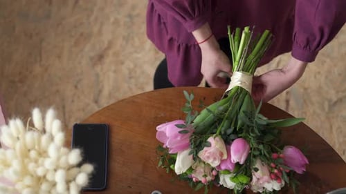 Close-up of Female Hands Tied in Bow Ribbon on Bouquet
