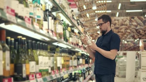 Male Visitor is Choosing White Wine in a Winery Reading Inscriptions on Bottle